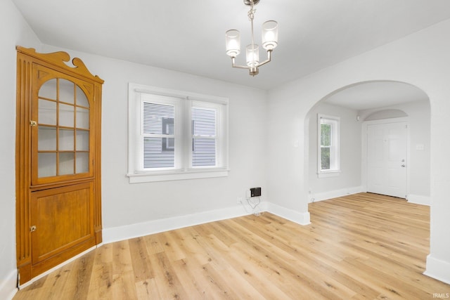 2318 Dodge Ave, Fort Wayne, IN 46805 - empty room with arched walkways, light wood-style floors, and a chandelier