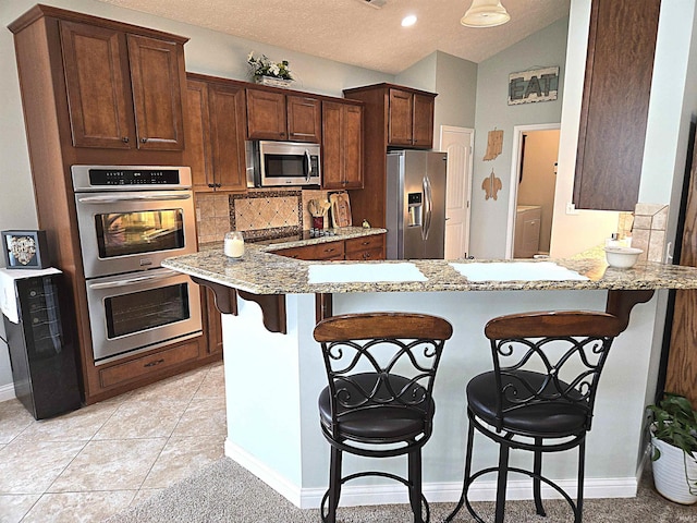 3520 Lintel Dr, West Lafayette, IN 47906 - kitchen featuring stainless steel appliances, light stone countertops, tasteful backsplash, a breakfast bar area, and a peninsula