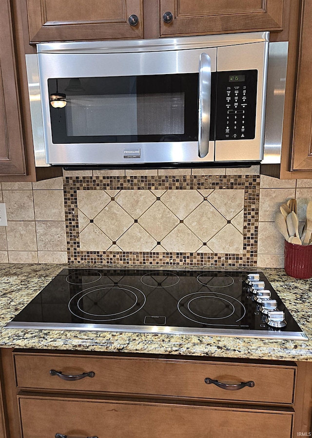 3520 Lintel Dr, West Lafayette, IN 47906 - kitchen view of stainless steel microwave, tasteful backsplash, black electric cooktop, and light stone countertops