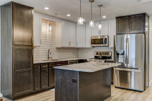 904-3 Reyling Dr, Jasper, IN 47546 - kitchen with stainless steel appliances, dark brown cabinets, light wood-type flooring, a center island, and light stone countertops