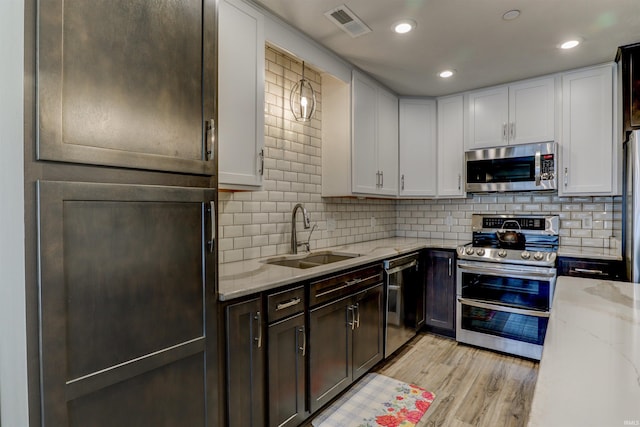 904-3 Reyling Dr, Jasper, IN 47546 - kitchen featuring appliances with stainless steel finishes, light stone countertops, light wood-type flooring, decorative backsplash, and white cabinetry