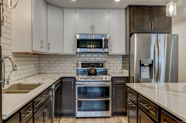 904-3 Reyling Dr, Jasper, IN 47546 - kitchen with appliances with stainless steel finishes, dark brown cabinetry, light stone countertops, light wood finished floors, and tasteful backsplash