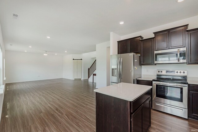 17951 Paula Walk, Westfield, IN 46074 - kitchen featuring stainless steel appliances, a center island, dark brown cabinets, dark wood-type flooring, and a barn door
