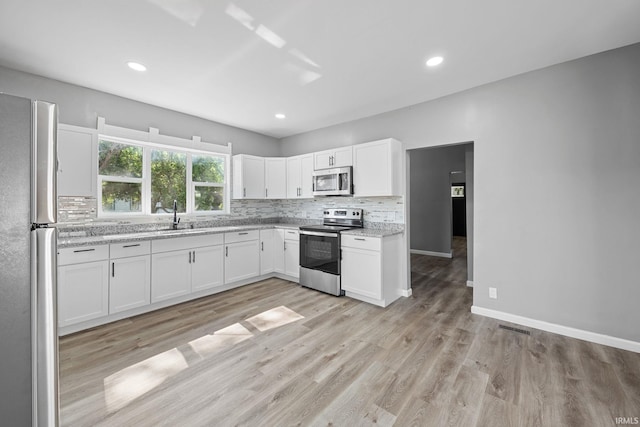 809 E 5th St, Fowler, IN 47944 - kitchen featuring appliances with stainless steel finishes, tasteful backsplash, white cabinets, light wood-style flooring, and recessed lighting