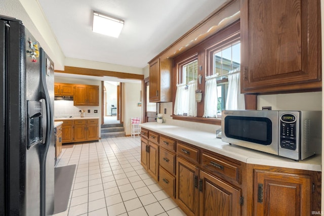 220 N Line St, Churubusco, IN 46723 - kitchen featuring black refrigerator with ice dispenser, stainless steel microwave, light countertops, brown cabinetry, and light tile patterned floors