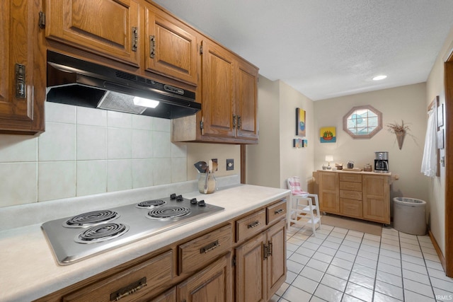 220 N Line St, Churubusco, IN 46723 - kitchen featuring under cabinet range hood, stainless steel electric stovetop, light countertops, a textured ceiling, and brown cabinetry