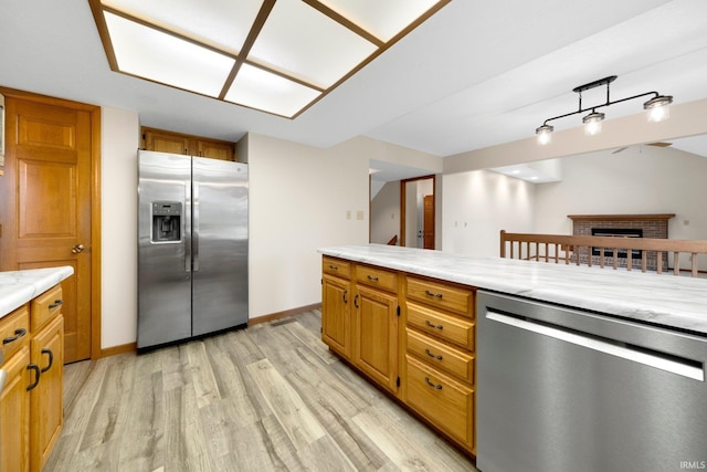 9106 Yellow Tree Ct, Fort Wayne, IN 46804 - kitchen featuring stainless steel appliances, light wood-style floors, light countertops, a fireplace, and brown cabinets