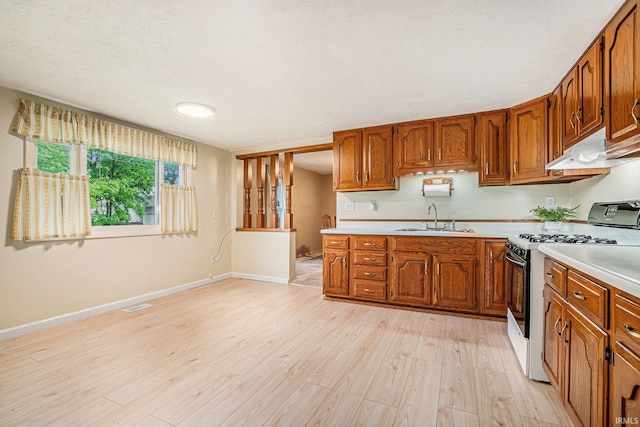 610 S Washington St, Warsaw, IN 46580 - kitchen with gas range, under cabinet range hood, light countertops, brown cabinets, and a textured ceiling