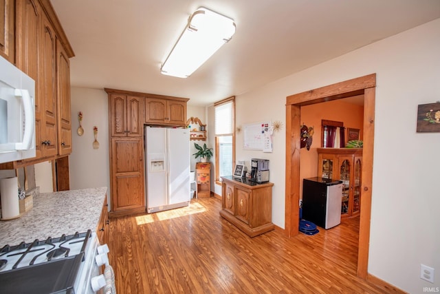 403 E Columbia St, Flora, IN 46929 - kitchen featuring white appliances, light wood-style floors, and brown cabinets