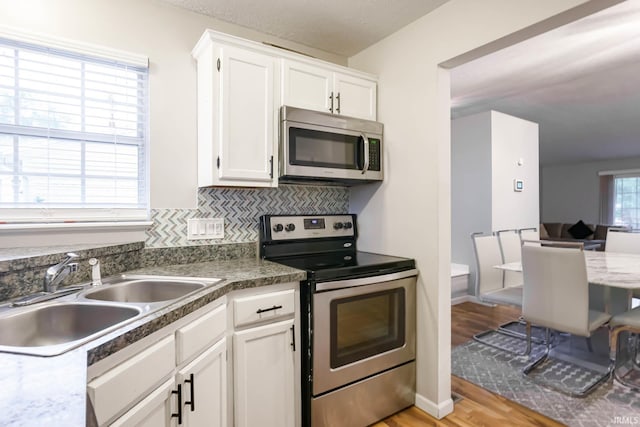 5209 Jenny Ln, Mishawaka, IN 46545 - kitchen featuring stainless steel appliances, white cabinetry, light wood-style floors, and backsplash