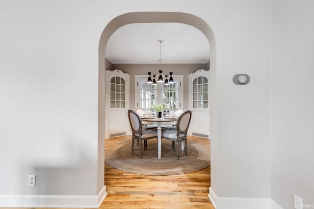 415 Wakewa Ave, South Bend, IN 46617 - dining room featuring arched walkways, light wood finished floors, a chandelier, and crown molding