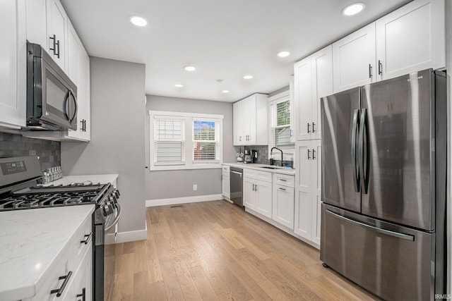1414 Longfellow Ave, South Bend, IN 46615 - kitchen featuring appliances with stainless steel finishes, decorative backsplash, white cabinetry, recessed lighting, and light wood-style flooring