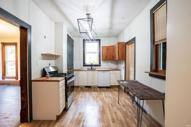 120 N Main St, Avilla, IN 46710 - kitchen featuring white dishwasher, stainless steel gas stove, light wood-type flooring, decorative backsplash, and a chandelier