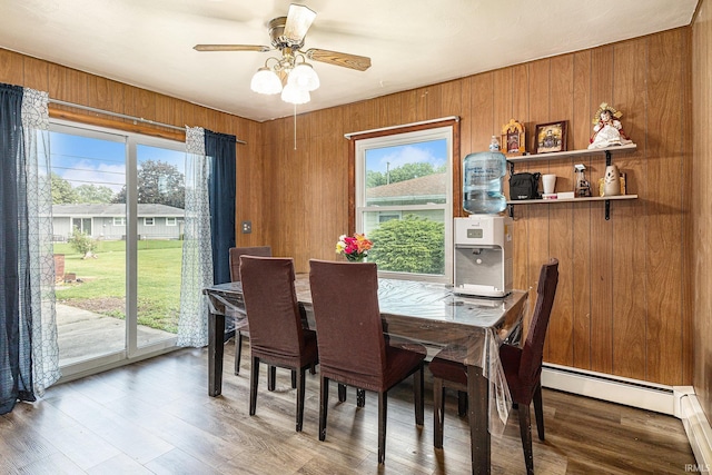 60220 Robin Hood Ln, Elkhart, IN 46517 - dining room featuring baseboard heating, plenty of natural light, a ceiling fan, wood walls, and wood finished floors
