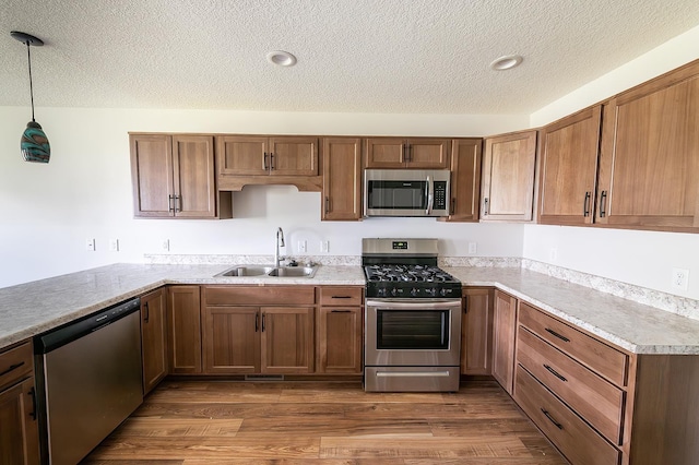 5205 Pigeon Creek Ct, Fort Wayne, IN 46825 - kitchen with appliances with stainless steel finishes, light countertops, a textured ceiling, brown cabinetry, and wood finished floors