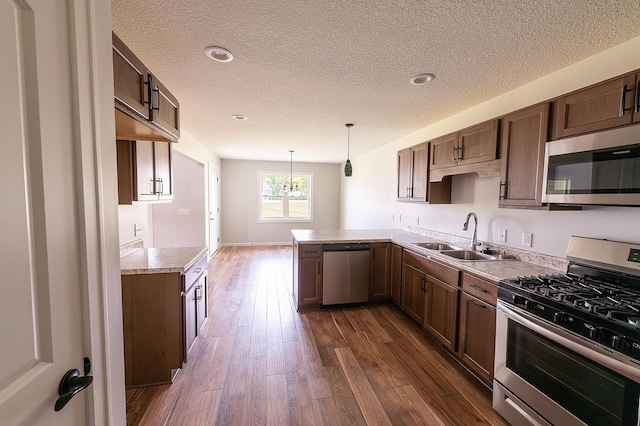5205 Pigeon Creek Ct, Fort Wayne, IN 46825 - kitchen featuring stainless steel appliances, a textured ceiling, dark wood finished floors, light countertops, and a peninsula