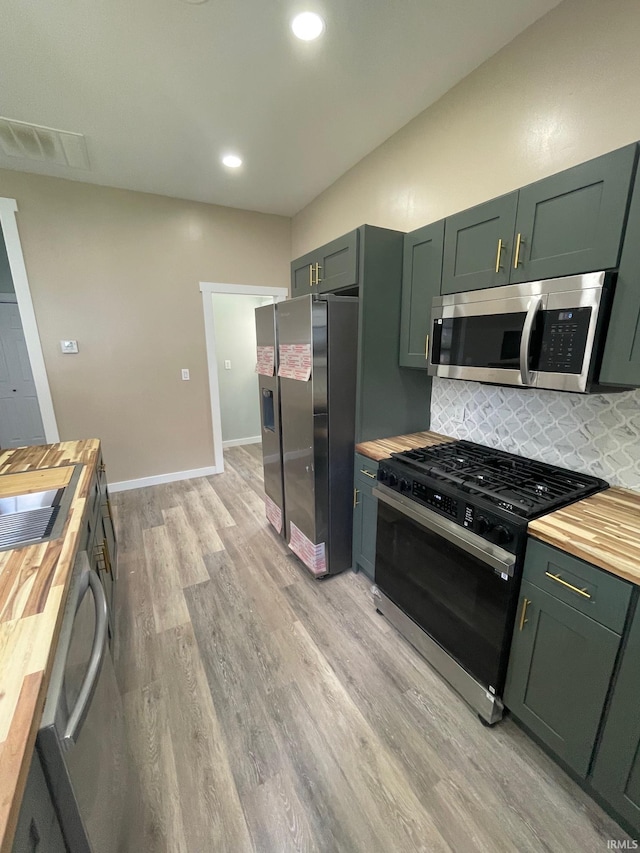 312 E 2nd St, Bicknell, IN 47512 - kitchen featuring butcher block counters, appliances with stainless steel finishes, green cabinets, light wood finished floors, and tasteful backsplash