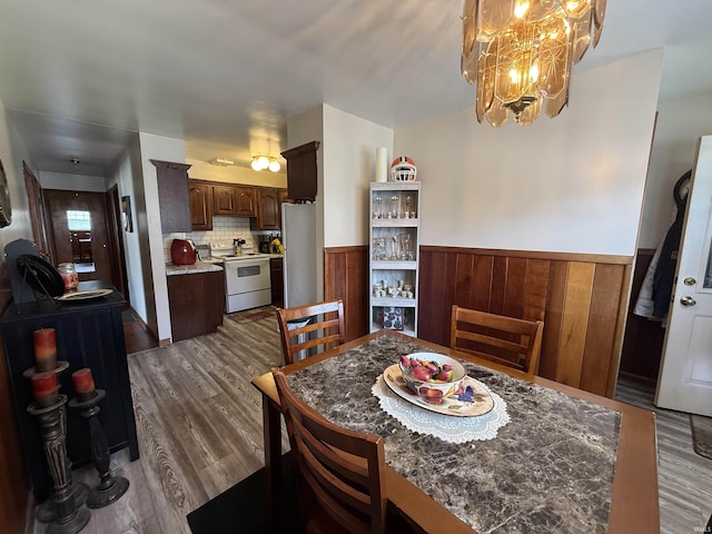 305 S Grove St, Odon, IN 47562 - dining space with dark wood-style floors, a chandelier, wainscoting, and wood walls