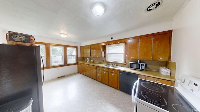 1219 Oakland St, Fort Wayne, IN 46808 - kitchen featuring white electric stove, freestanding refrigerator, stainless steel microwave, dishwasher, and brown cabinets