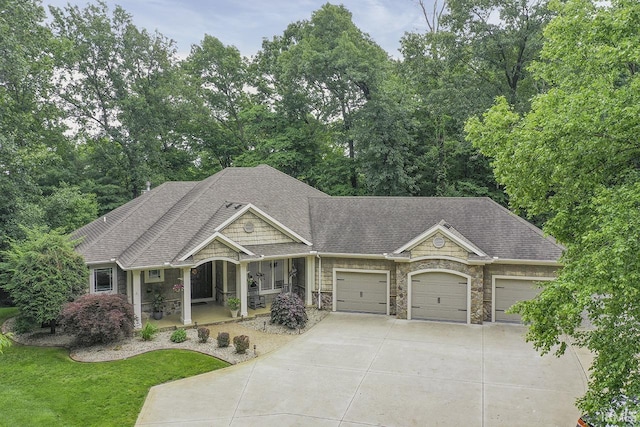 55623 Little Creek Ln, Middlebury, IN 46540 - view of front facade featuring covered porch, stone siding, a garage, concrete driveway, and roof with shingles