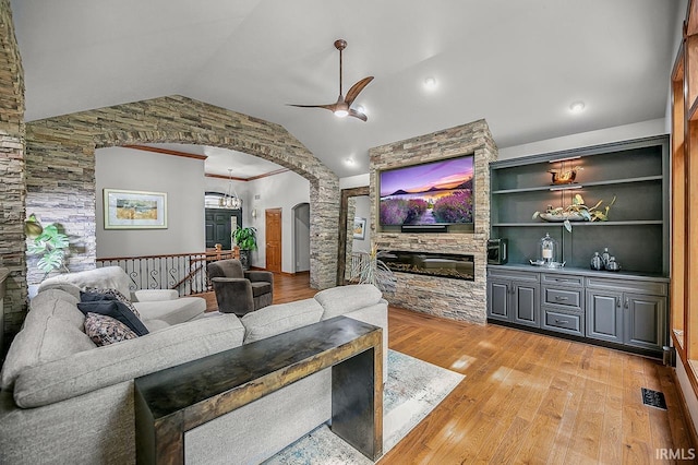 55623 Little Creek Ln, Middlebury, IN 46540 - living room with arched walkways, a ceiling fan, light wood-type flooring, a stone fireplace, and vaulted ceiling