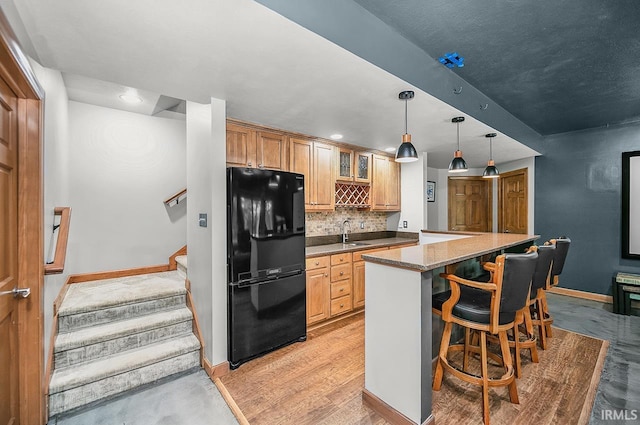 55623 Little Creek Ln, Middlebury, IN 46540 - kitchen featuring freestanding refrigerator, a breakfast bar, tasteful backsplash, glass insert cabinets, and hanging light fixtures