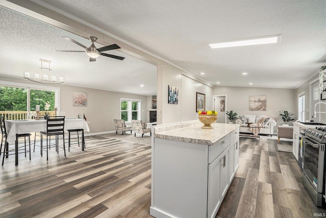 17725 Douglas Rd, South Bend, IN 46635 - kitchen with open floor plan, stainless steel stove, a textured ceiling, wood finished floors, and ornamental molding
