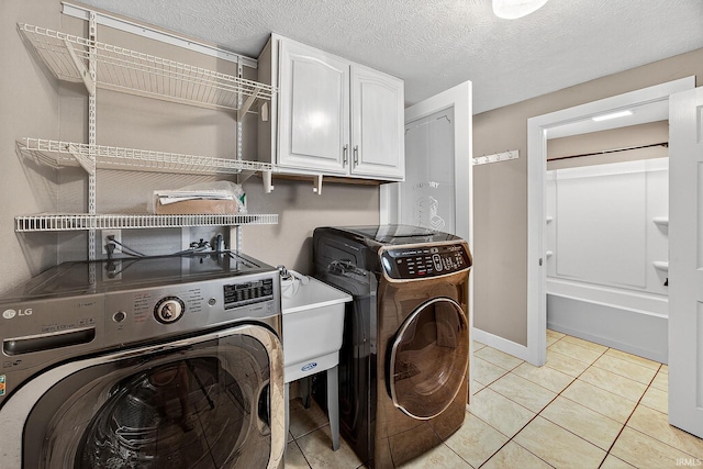 119 Towle Ave, Mishawaka, IN 46544 - washroom featuring cabinet space, independent washer and dryer, light tile patterned floors, and a textured ceiling