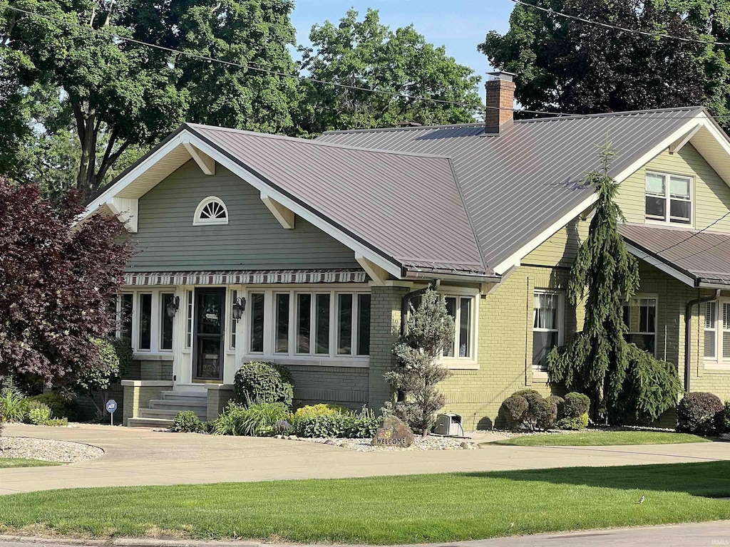 2726 E Jackson Blvd, Elkhart, IN 46516 - view of front of house featuring a chimney, brick siding, a front lawn, and a metal roof