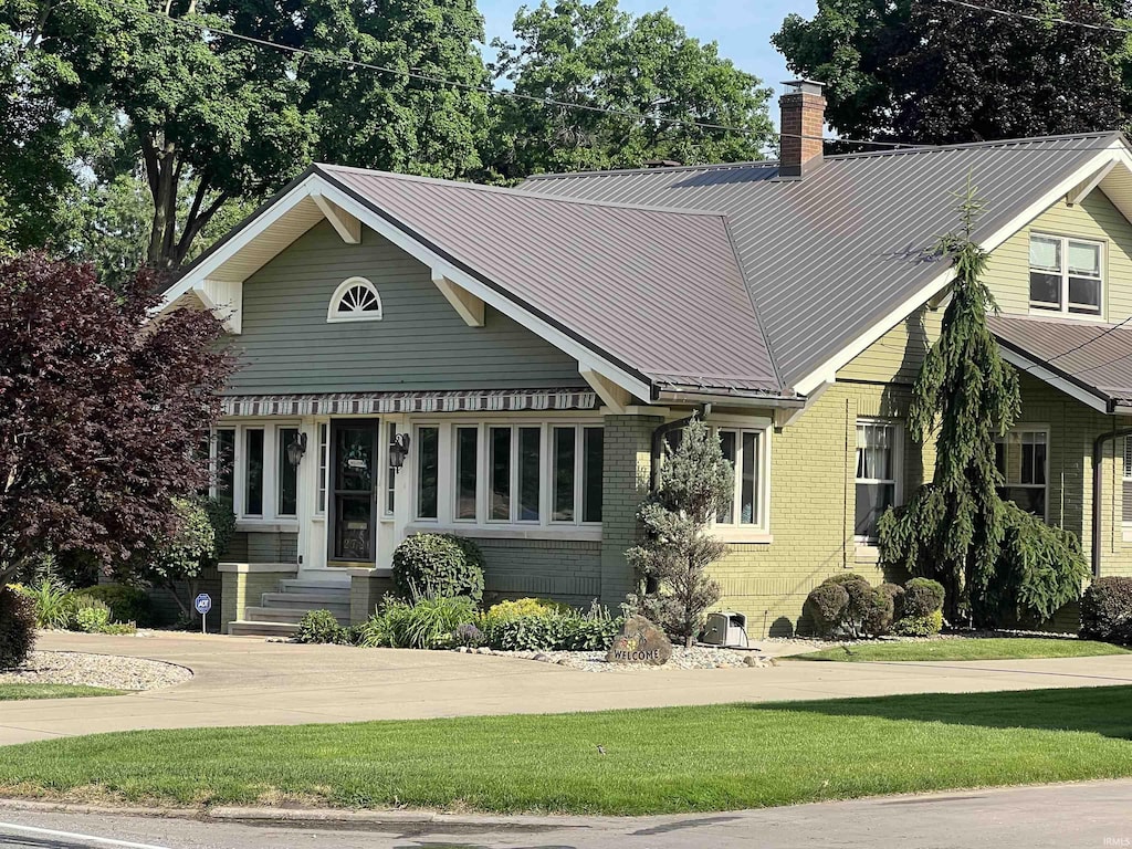 2726 E Jackson Blvd, Elkhart, IN 46516 - view of front of home with a chimney, brick siding, a front lawn, and a metal roof