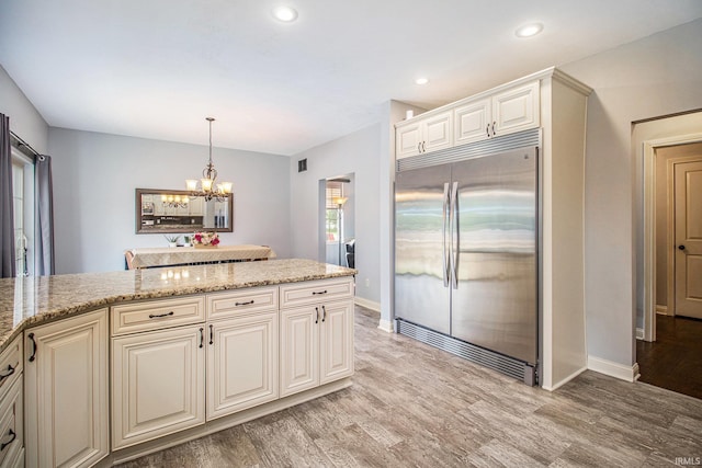 11999 Loughlin Dr, Mishawaka, IN 46545 - kitchen featuring built in refrigerator, light wood-style flooring, a chandelier, light stone countertops, and recessed lighting