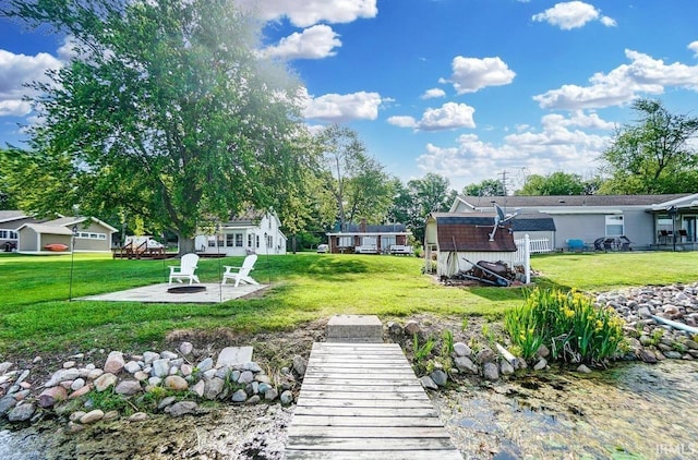 1049 Chapman Lake Dr, Warsaw, IN 46582 - view of grassy yard featuring an outdoor fire pit, a patio area, and an outdoor structure