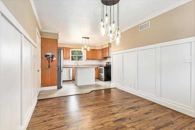 51268 Channel Ct, Elkhart, IN 46514 - kitchen with stainless steel appliances, a chandelier, hardwood / wood-style flooring, brown cabinets, and crown molding