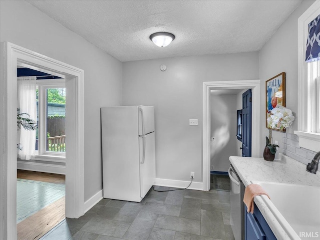 1310 W Jefferson Blvd, Fort Wayne, IN 46802 - kitchen with freestanding refrigerator, blue cabinetry, dishwasher, and a textured ceiling