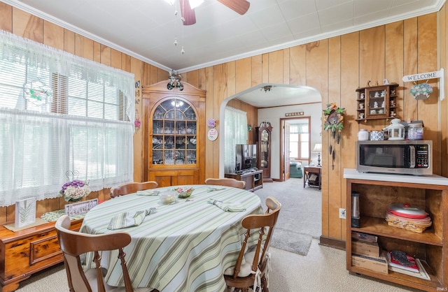 3721 Claremont Ave, Evansville, IN 47712 - dining area featuring arched walkways, crown molding, wooden walls, light colored carpet, and a ceiling fan
