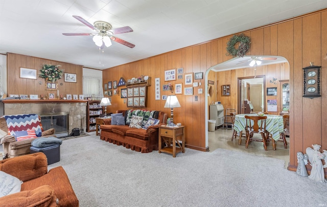 3721 Claremont Ave, Evansville, IN 47712 - living room featuring ceiling fan, arched walkways, wood walls, a fireplace, and carpet floors