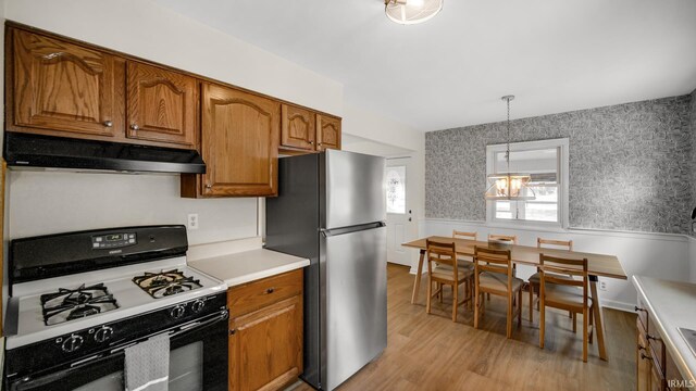 1897 Lakeshore Dr, Walkerton, IN 46574 - kitchen featuring range with gas cooktop, under cabinet range hood, freestanding refrigerator, wainscoting, and light wood-style flooring