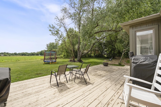 3865 E Forest Glen Ave, Leesburg, IN 46538 - wooden terrace featuring a trampoline, a yard, an outdoor fire pit, and outdoor dining space