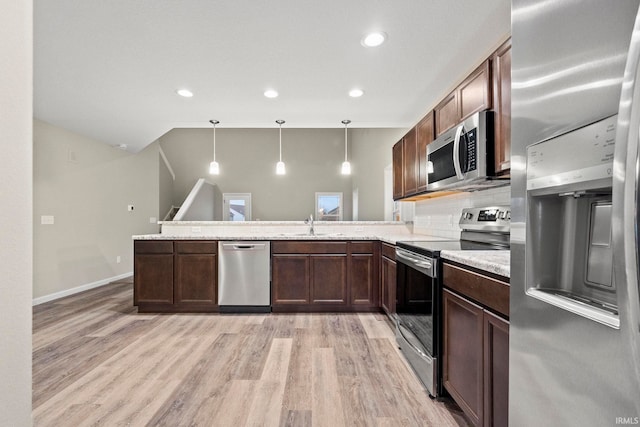 10263 Tirian Pl, Fort Wayne, IN 46835 - kitchen featuring appliances with stainless steel finishes, light wood finished floors, a peninsula, hanging light fixtures, and decorative backsplash