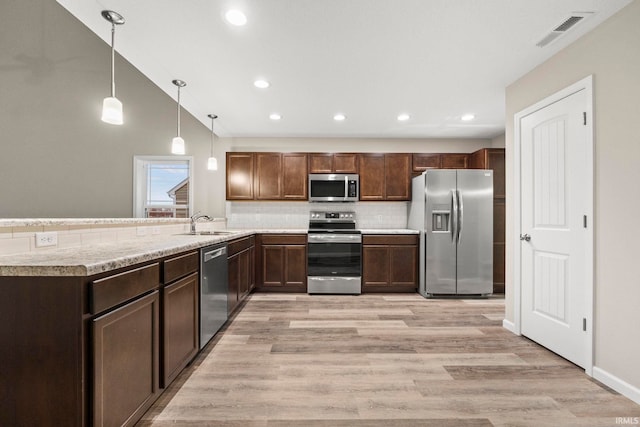 10263 Tirian Pl, Fort Wayne, IN 46835 - kitchen with appliances with stainless steel finishes, backsplash, light countertops, a peninsula, and light wood-style floors