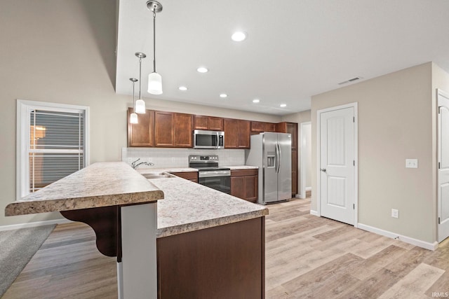 10263 Tirian Pl, Fort Wayne, IN 46835 - kitchen featuring appliances with stainless steel finishes, light countertops, a breakfast bar area, a peninsula, and hanging light fixtures
