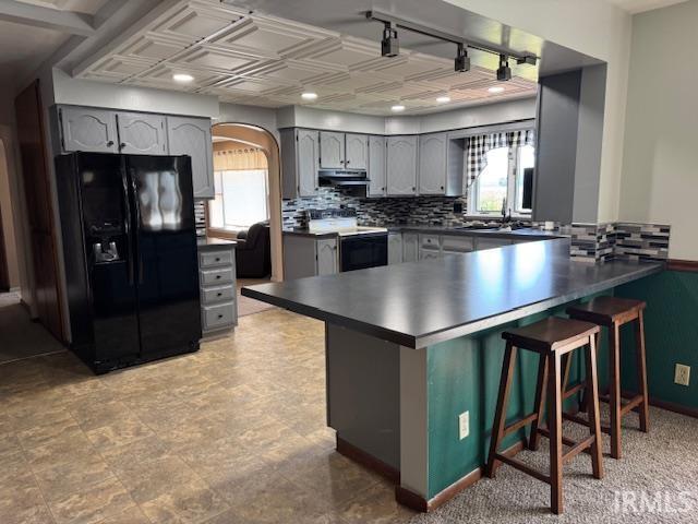 7737 N 100 E Rd, Lucerne, IN 46950 - kitchen with black fridge with ice dispenser, electric range oven, gray cabinetry, a peninsula, and ventilation hood