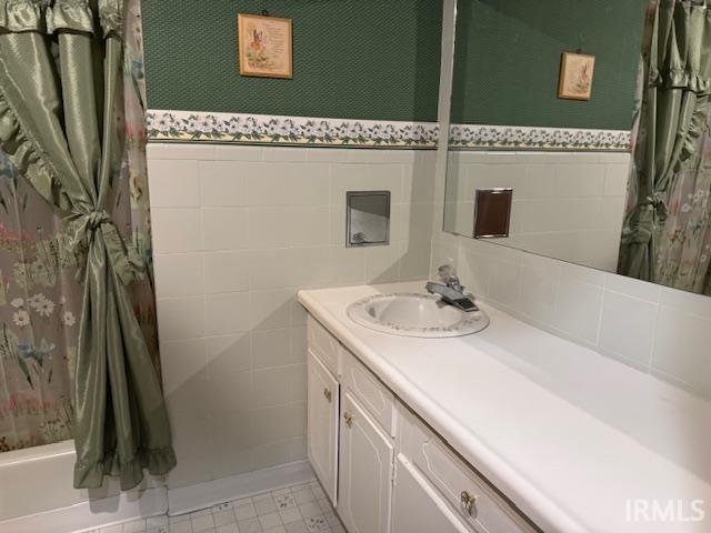 7737 N 100 E Rd, Lucerne, IN 46950 - bathroom featuring vanity, tile walls, a shower with curtain, a wainscoted wall, and wallpapered walls