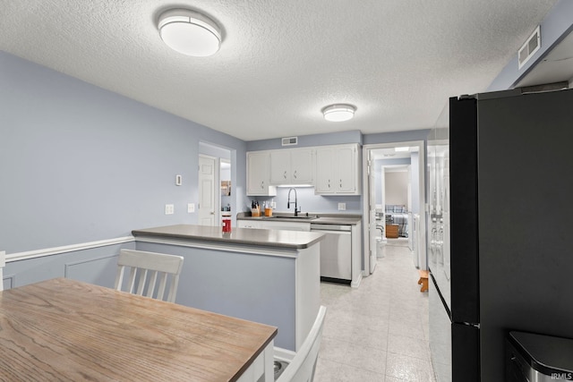 17135 Old 24 Rd, Woodburn, IN 46797 - kitchen with freestanding refrigerator, stainless steel dishwasher, white cabinets, a textured ceiling, and a peninsula