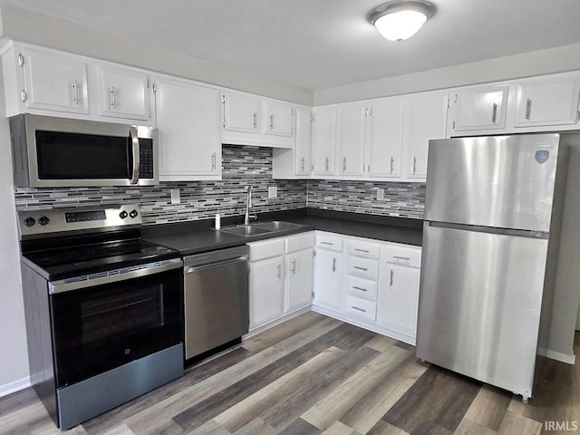 104 Fremont Ln, Decatur, IN 46733 - kitchen featuring stainless steel appliances, dark countertops, white cabinetry, and wood finished floors