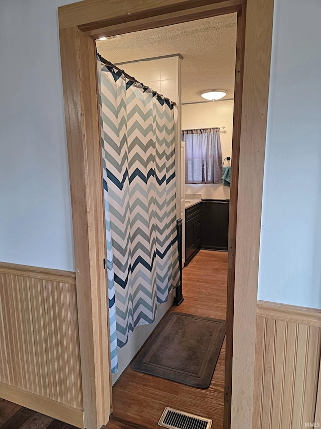 826 SE 2nd St, Washington, IN 47501 - bathroom featuring wainscoting, curtained shower, wood walls, and wood finished floors