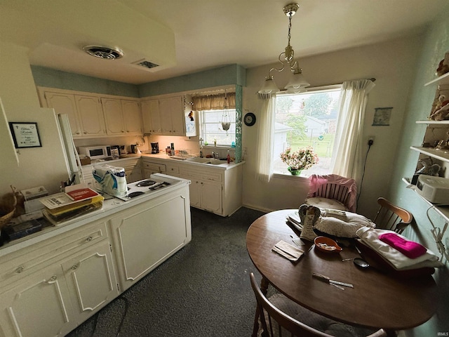 100 S Fairlawn Ave, Evansville, IN 47714 - kitchen featuring dark colored carpet, light countertops, hanging light fixtures, white stovetop, and stainless steel microwave