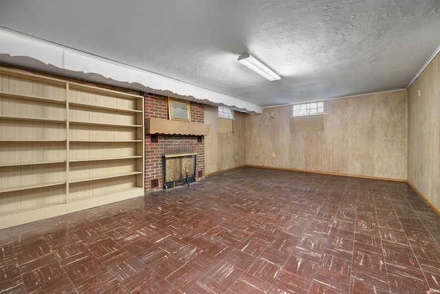 501 N Van Buren St, Auburn, IN 46706 - basement with a textured ceiling, dark flooring, wooden walls, a brick fireplace, and built in shelves