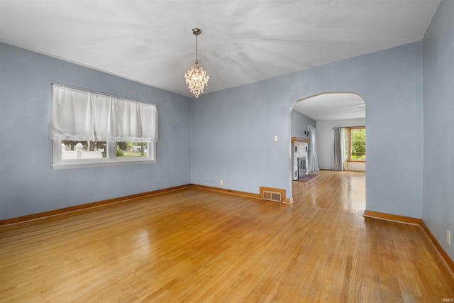 501 N Van Buren St, Auburn, IN 46706 - unfurnished room featuring arched walkways, light wood-type flooring, a chandelier, and a fireplace