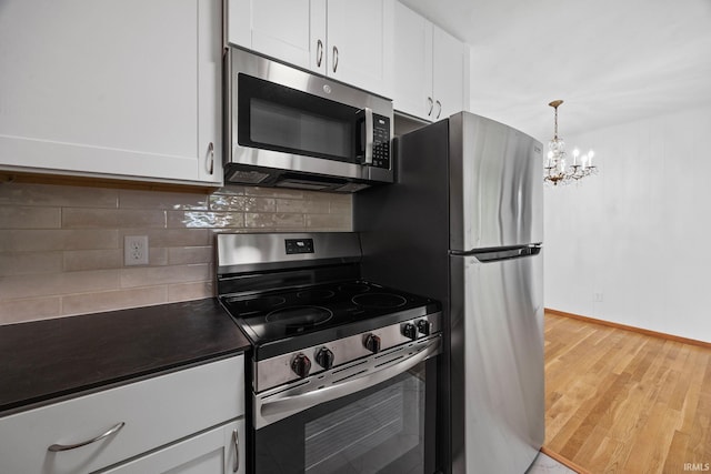 8416 S 400 W, Lafayette, IN 47909 - kitchen with appliances with stainless steel finishes, dark countertops, a chandelier, light wood-type flooring, and white cabinetry